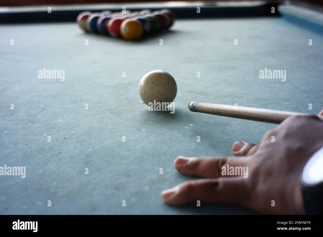 Nahaufnahme der Hand des Poolspielers, die sich auf den Start des Spiels vorbereitet. Die erste Bewegung des Spielens von Billard zerstört die fünfzehn Billardkugel-Formation, die Stockfoto