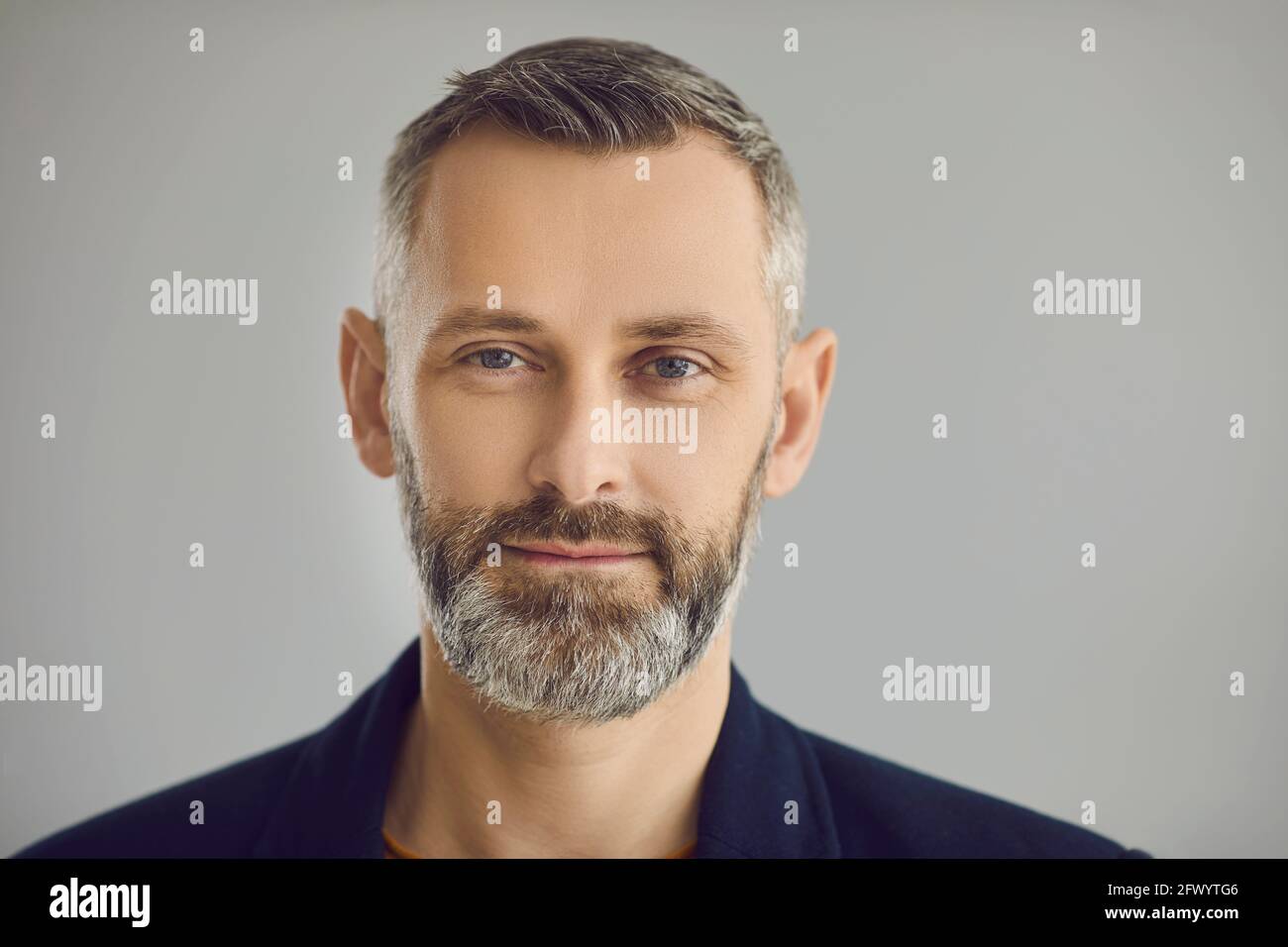 Porträt eines selbstbewussten, reifen Geschäftsmanns, der die Kamera anschaut Grauer Studiohintergrund Stockfoto