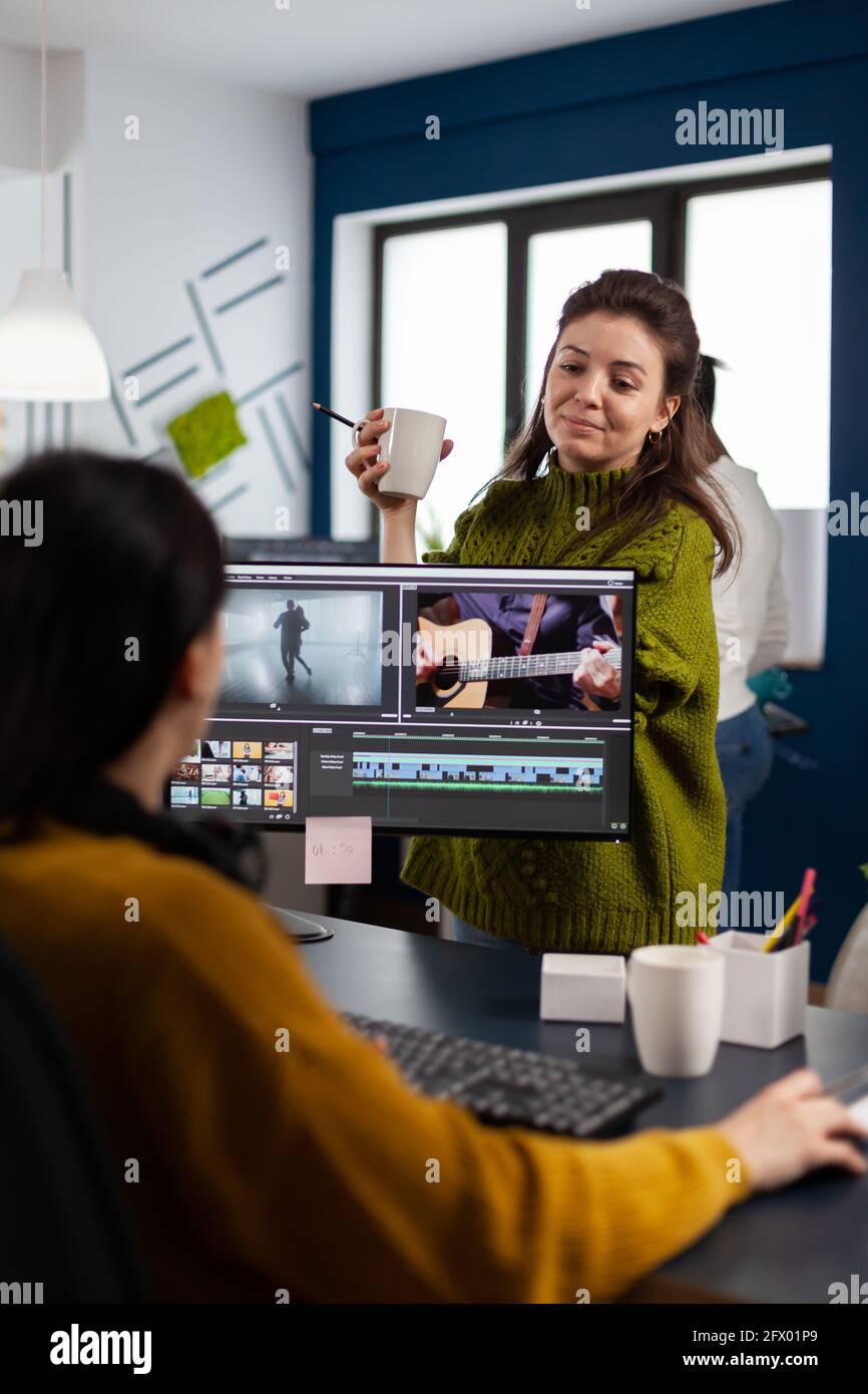 Frauen Videofilmer bearbeiten Videoprojekt erstellen Inhalte, Team von Bloggern sitzt in modernen Start-up-Büro-Studio. Der Manager erklärt die kollegialitäre Filmmontage, die in der Postproduktionssoftware arbeitet. Stockfoto