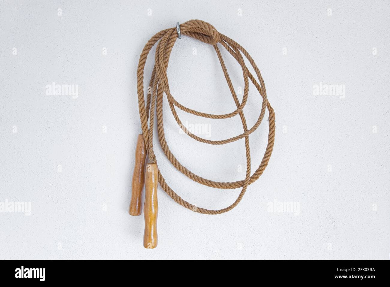 Ein altes Springseil, das an einer weißen Wand hängt. Stockfoto