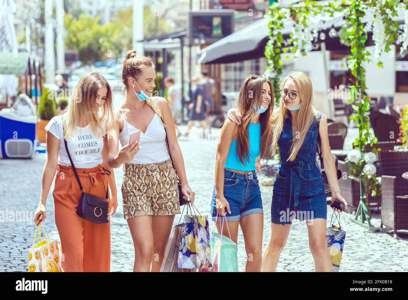 Glückliche junge Mädchen mit offenen Gesichtsmasken Spaß zu genießen Ein Tag zusammen Shopping in der City Street Stockfoto