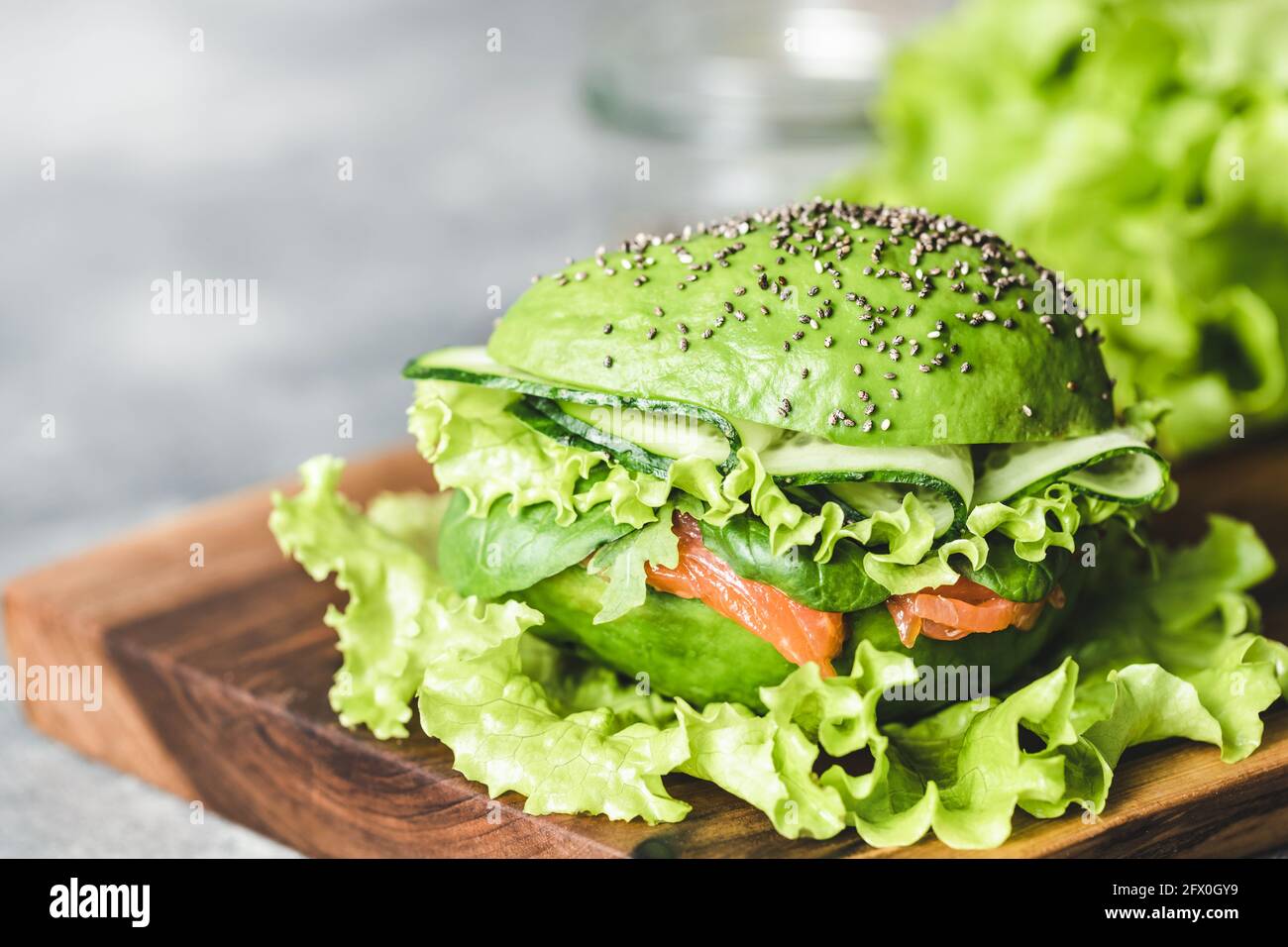 Avocado-Burger mit Lachs und Salat auf Holzbrett. Stockfoto