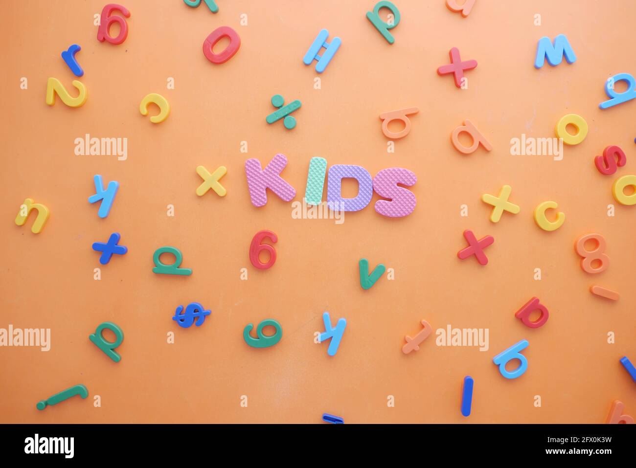 Bunte Plastikbuchstaben auf orangefarbenem Hintergrund, Draufsicht Stockfoto