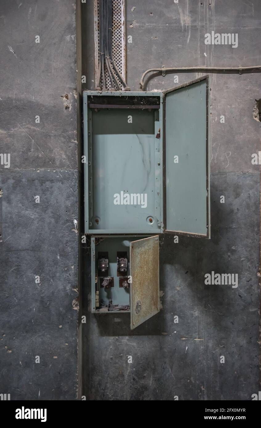 Alte Schalttafel leeren. Offener Verteilerkasten an beschädigter Betonwand im verlassenen Gebäude Stockfoto