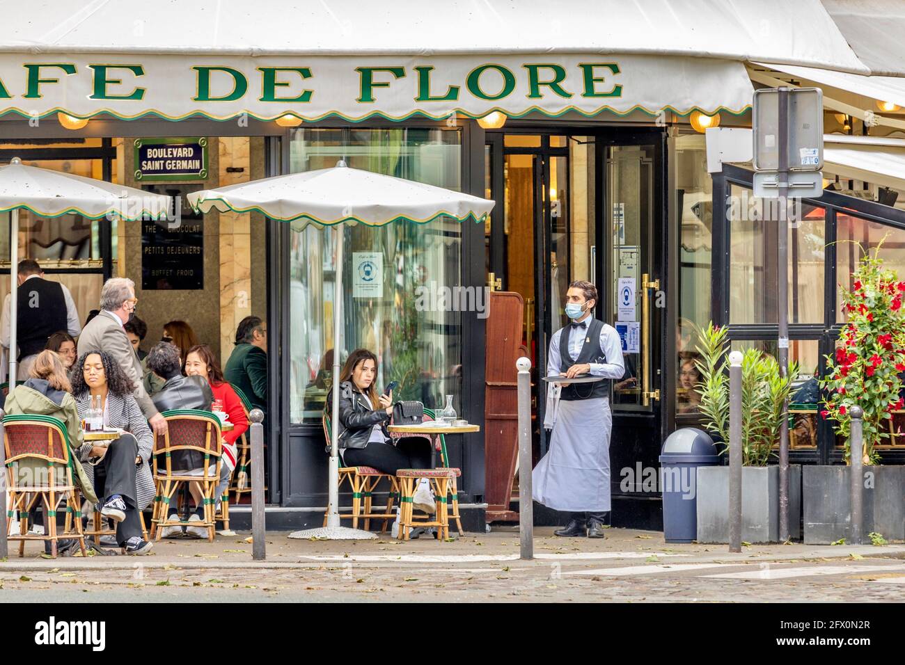 Paris, Frankreich - 19. Mai 2021: Tag nach der Sperre wegen Covid-19 in einem berühmten Pariser Café. Kellner tragen chirurgische Masken Stockfoto