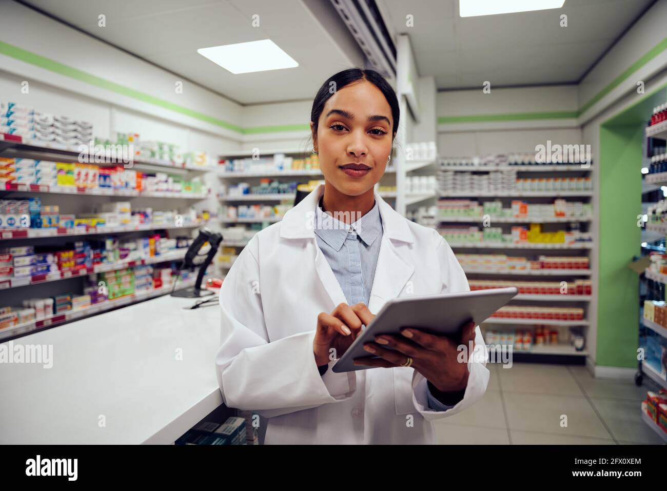 Porträt einer jungen afroamerikanischen Frau, die in der Nähe der Theke steht Apotheke mit digitalem Tablet Stockfoto