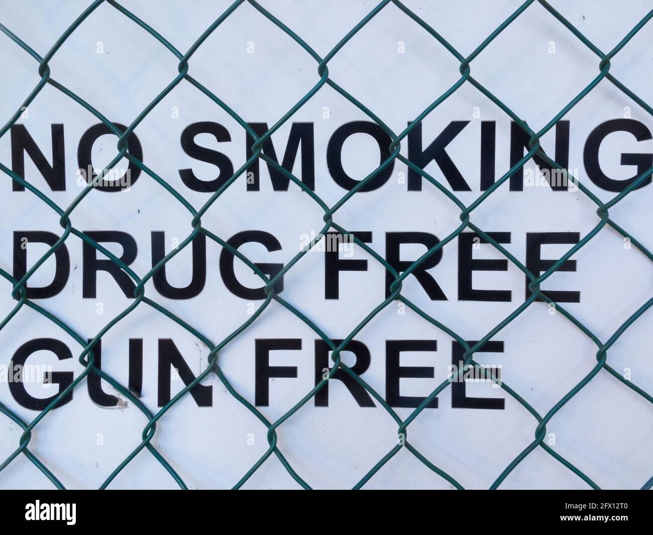 zeichen mit Worten oder Text, Rauchen verboten, drogenfrei, ohne Waffen, gegen einen Zaun an einem Schulkonzept Sicherheit und Sicherheit in der Bildung Stockfoto