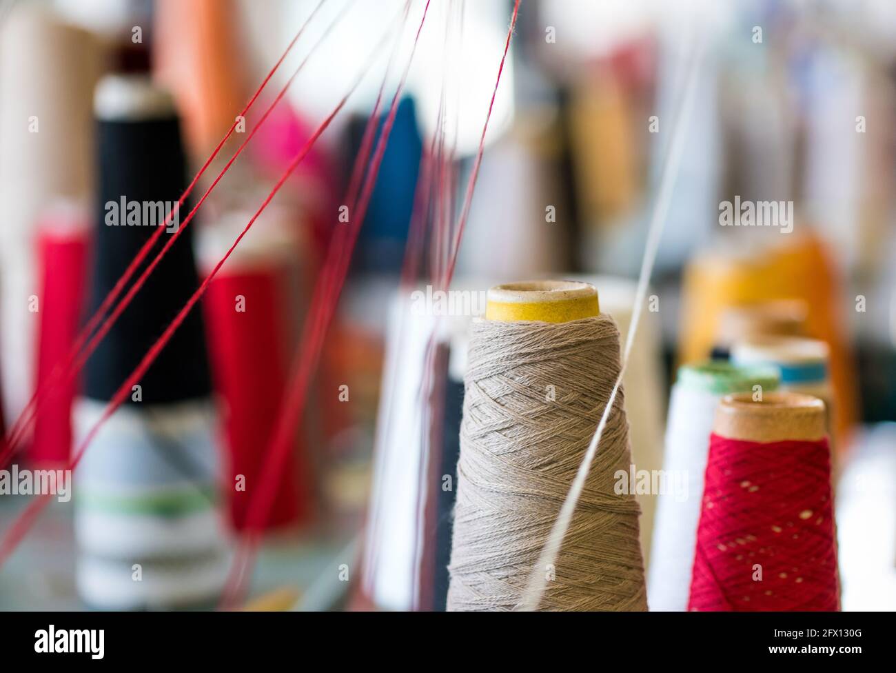 Nahaufnahme von Kegeln aus verschiedenen Farben von Kaschmirfäden In einer Strickfabrik, in der Wolltextilien für die Mode hergestellt werden Branche Stockfoto
