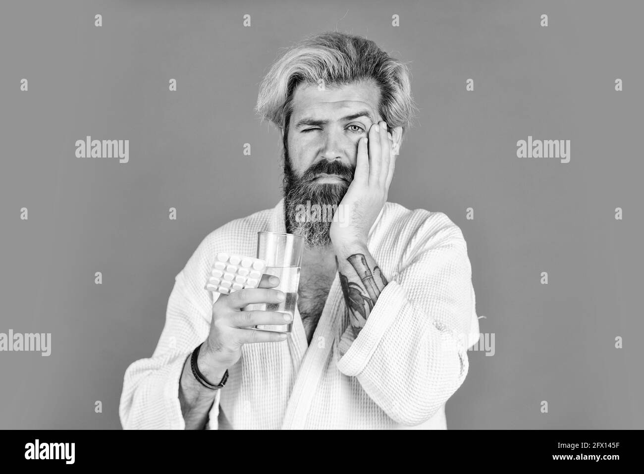 Zahnschmerzen. Bärtiger Hipster entspannen sich im Bett. Er braucht Bettruhe. Folgen von Kater. Mann nehmen Pille gegen Schlaflosigkeit. Haben schreckliche Kopfschmerzen Stockfoto