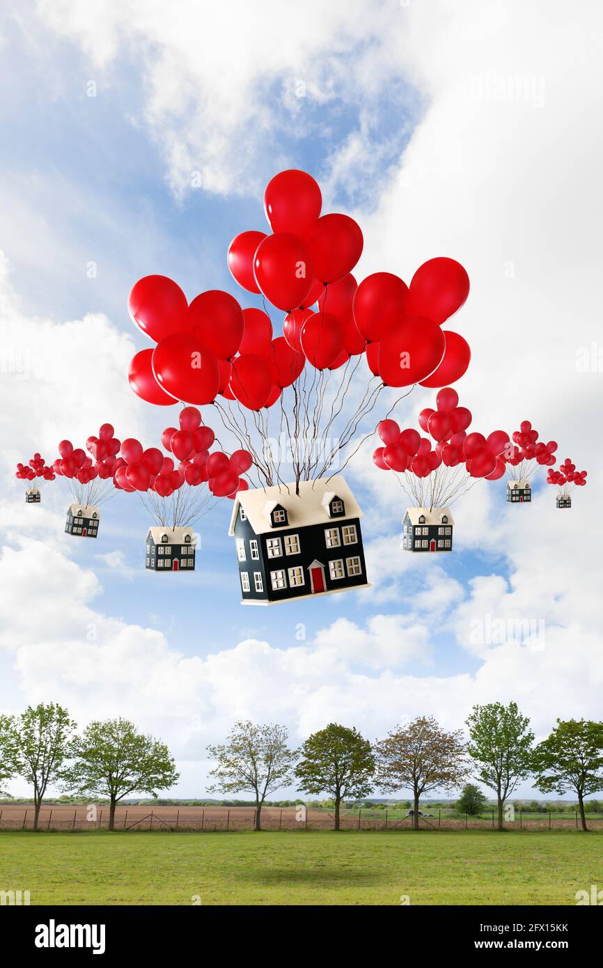 Wohnumsiedlungskonzept mit Häusern, die mit roten Ballons über die britische Landschaft schweben. Immobilienmakler und Immobilienkonzept. Stockfoto