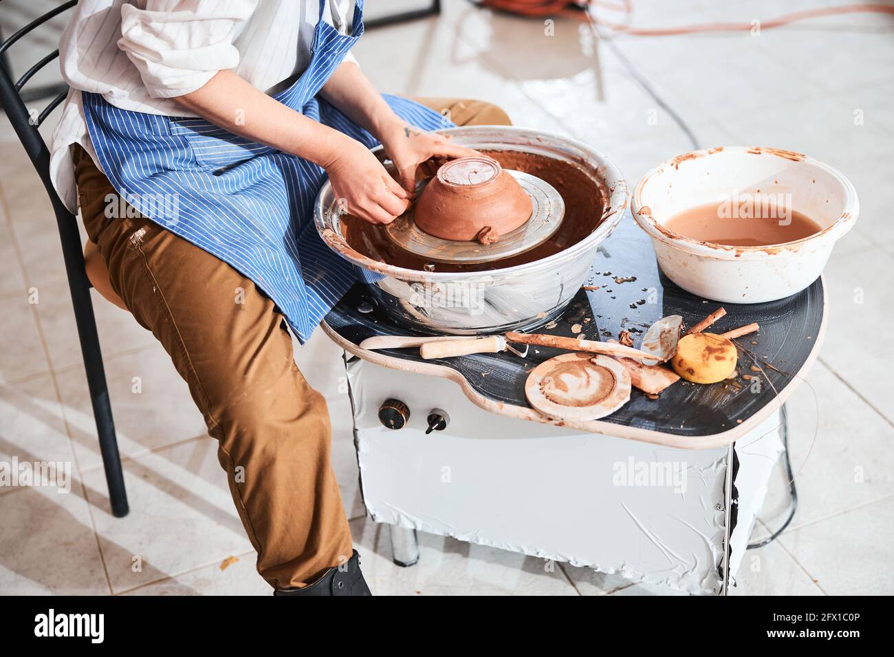 Töpferkünstler platziert Tonklumpen in der Nähe des Schalenrandes auf dem Rad Stockfoto