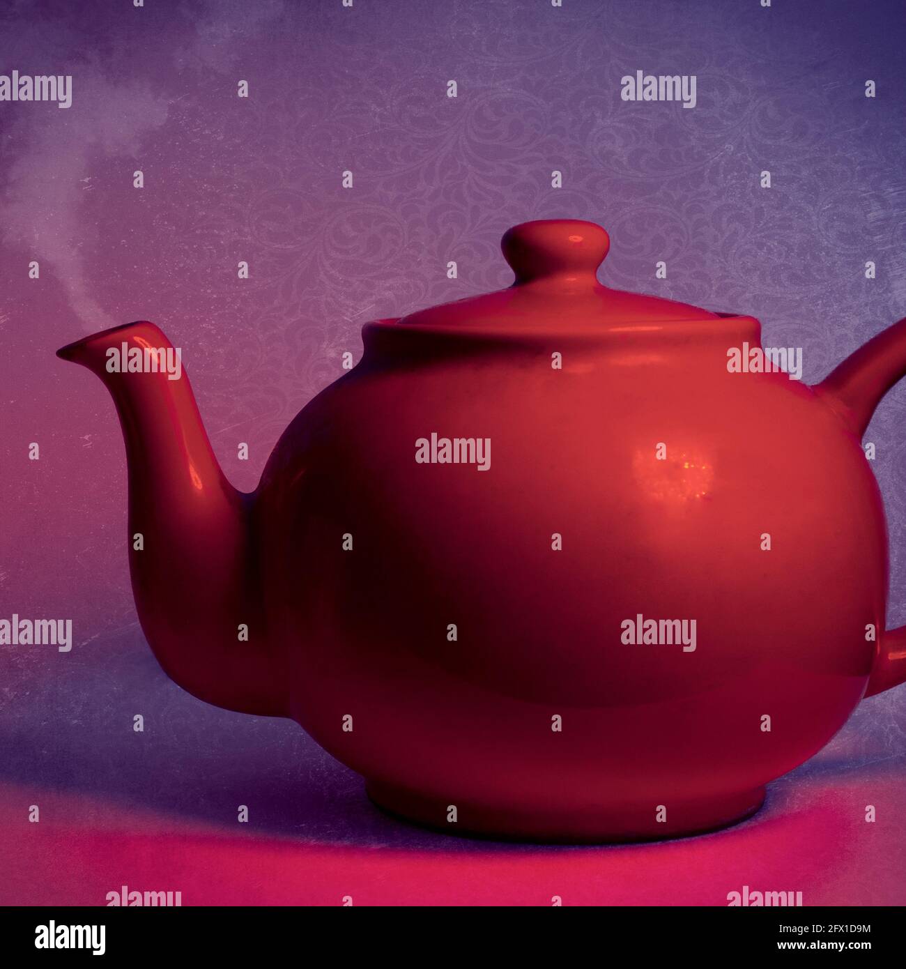 Rote Teekannen vor einem violetten und roten Hintergrund Stockfoto