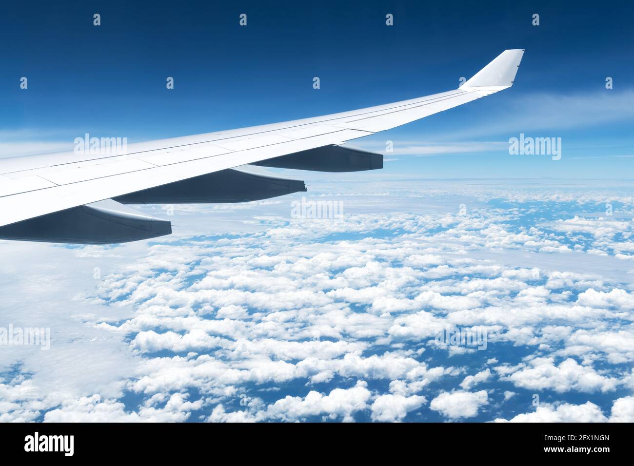 Blick auf Wolken und Flügel aus einem Flugzeugfenster. Reise- und Urlaubskonzept Stockfoto
