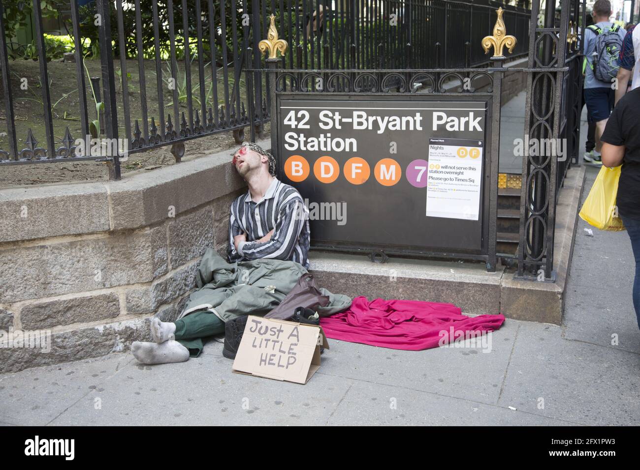 Obdachloser schläft in der Sonne, während er vor dem Bryant Park in der 40th Street und 6th Avenue in Manhattan um Hilfe bittet. Stockfoto