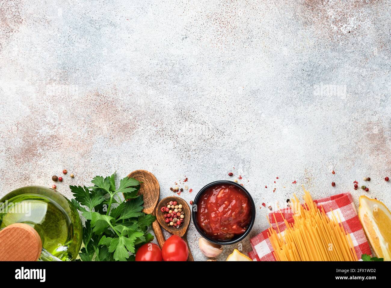 Pasta-Hintergrund. Pasta Spaghetti, Tomatenketchup-Sauce, Olivenöl, Gewürze, Petersilie, Und frische Tomaten auf einem hellgrauen Schiefertisch. Kochen von Speisen Stockfoto