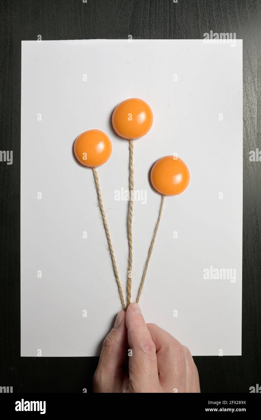 Konzept Hand hält Ballons Haufen aus Eigelb Stockfoto