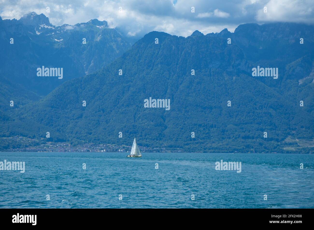 Ein Segelboot auf dem Lac Leman, Schweiz, mit umliegenden Bergen an einem Sommertag Stockfoto
