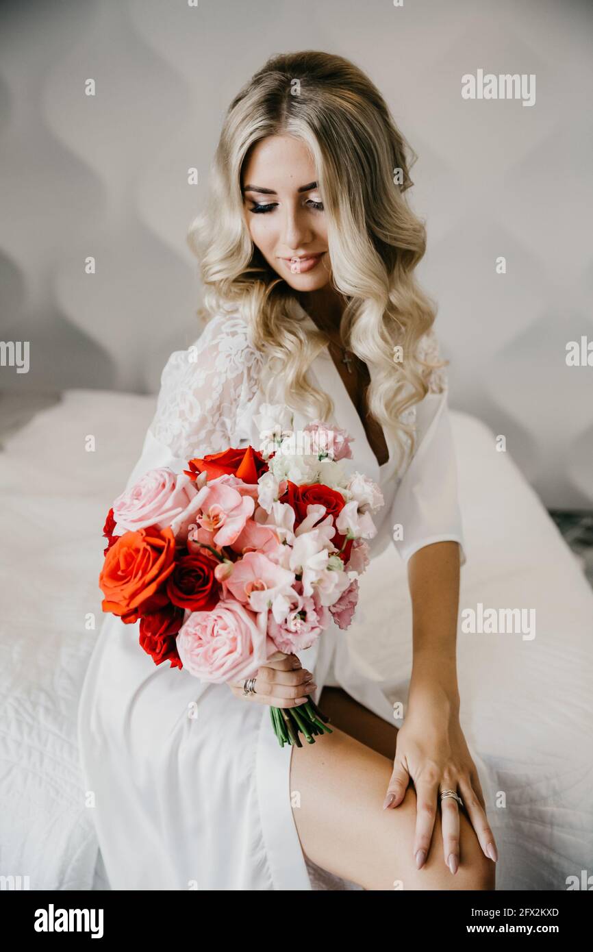 Elegante blonde Braut in Weiß mit einem Hochzeitsstrauß gekleidet. Hochzeitskonzept Stockfoto