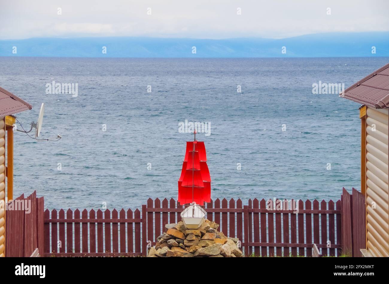 Schiff hinter dem Zaun, Brigantine mit roten Segeln vor dem Hintergrund des offenen Meeres. Platz für Text kopieren, Konzept der Freiheitsbeschränkung Stockfoto