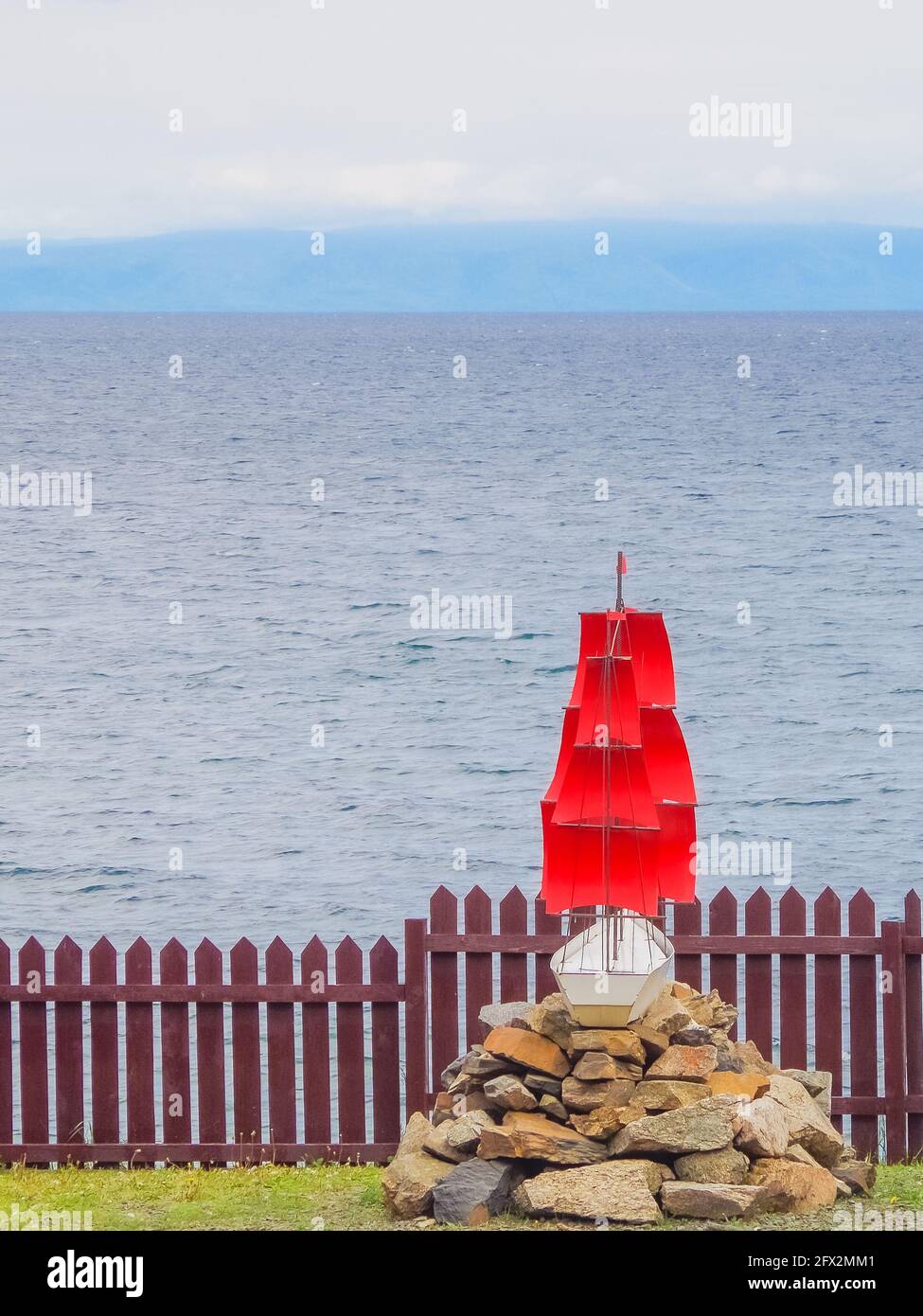Schiff hinter dem Zaun, Brigantine mit roten Segeln vor dem Hintergrund des offenen Meeres. Platz für Text kopieren, Konzept der Freiheitsbeschränkung Stockfoto