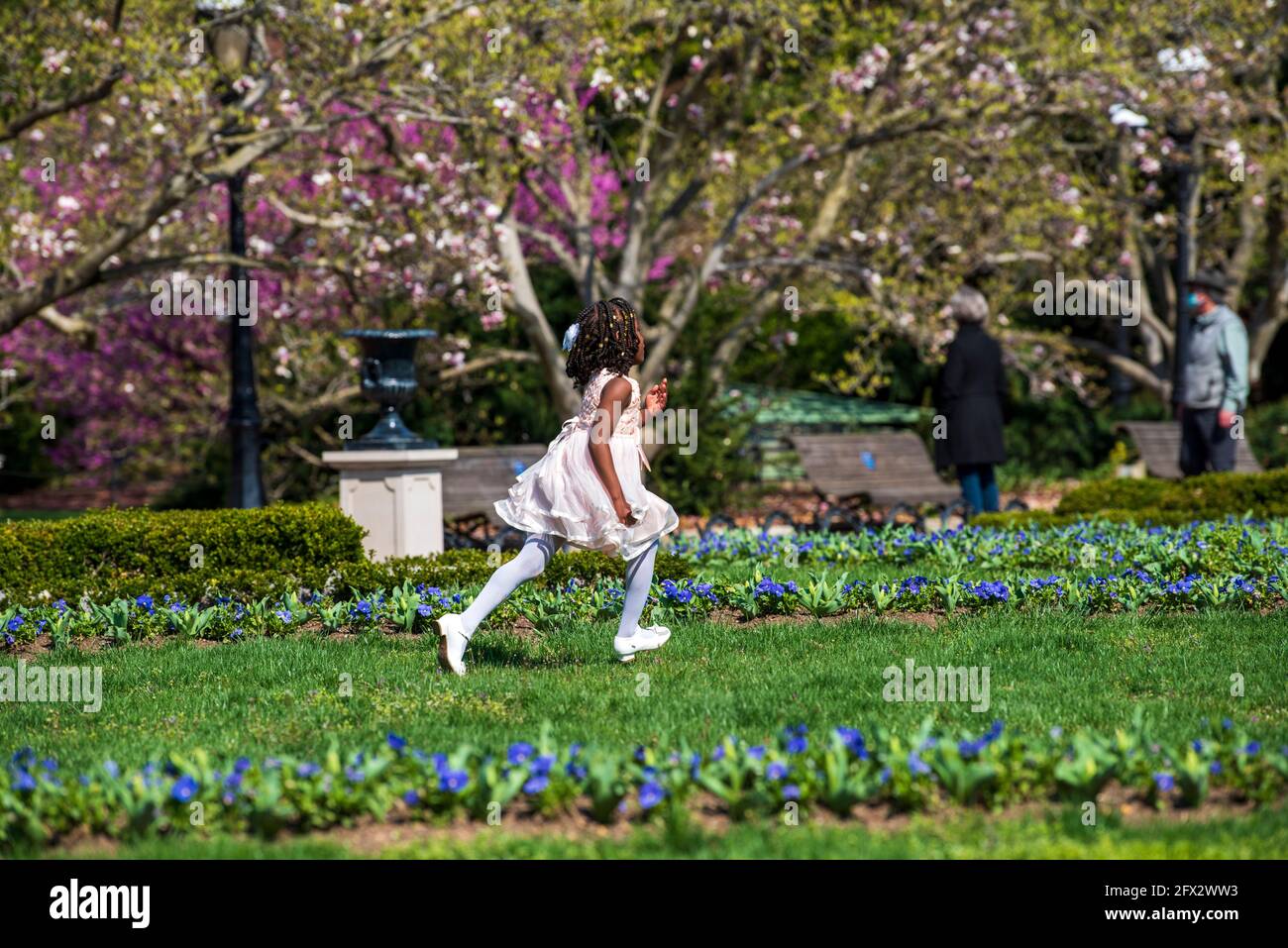 Ein junges afroamerikanisches Mädchen, das sich in ihrer Osterschönster verkleidet, durchläuft die Gärten des Smithsonian Castle in Washington, D.C. Stockfoto