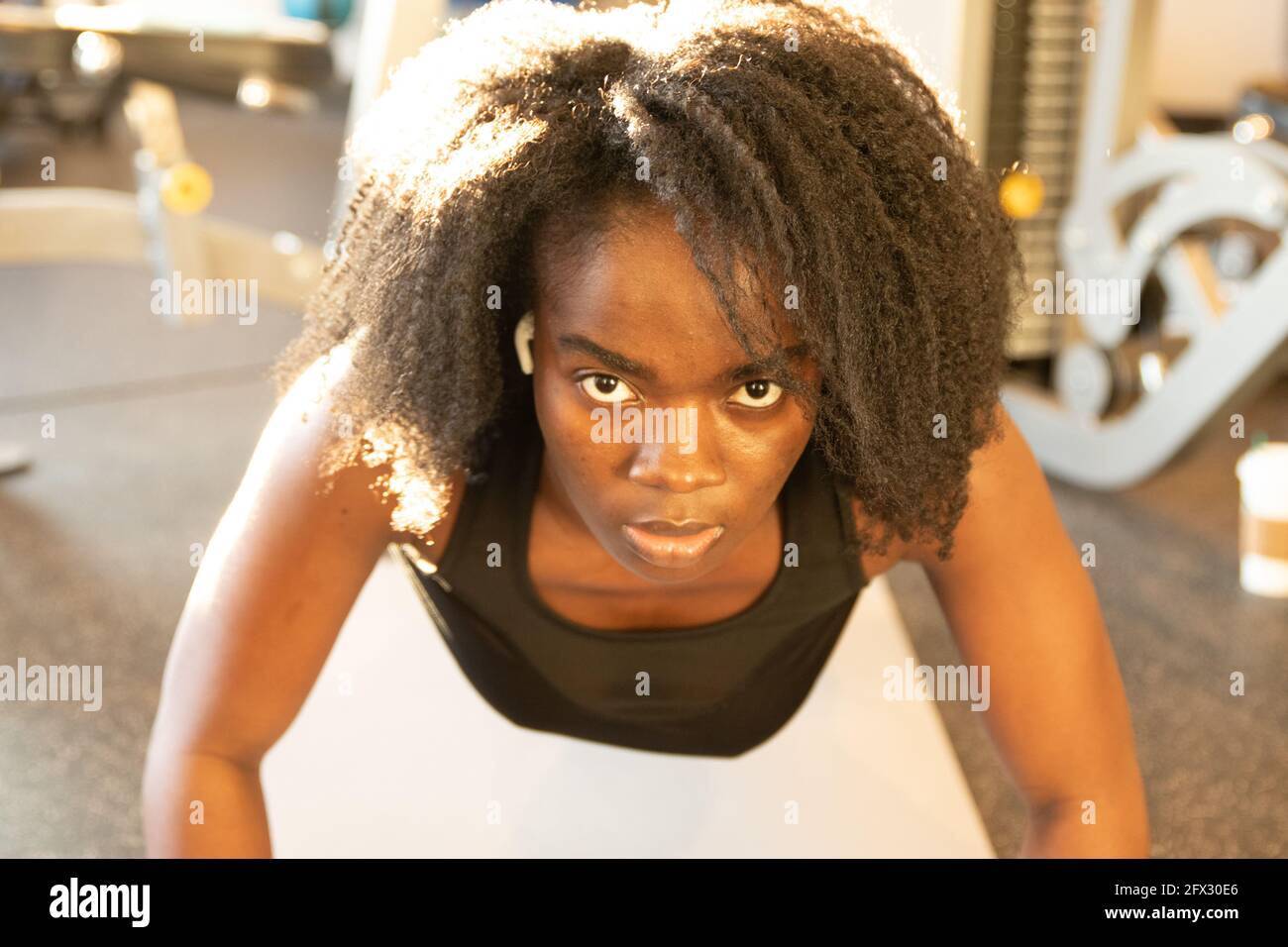 Ernsthafte junge Frau auf Yoga-Matte Training. Nahaufnahme, eine Person, afroamerikanisch, schwarze Frau, afrikanisches Modell, Natürliche Haare Frau, lächelndes Gesicht, fit Stockfoto