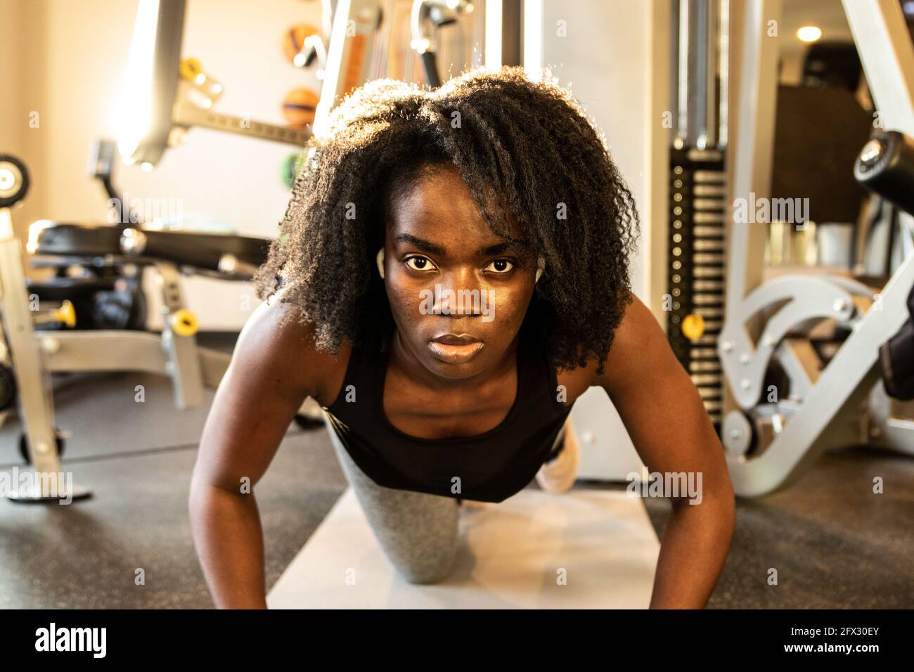 Schwarze Frau trainieren in der Halle im Fitness-Studio tun Push-up, eine Person, Nahaufnahme Porträt, natürliche Haare, Blick auf die Kamera, afroamerikanisch, Bodybuildin Stockfoto