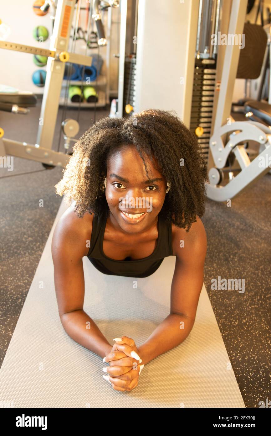 Starke schöne Fitness-Mädchen in athletischen Workout Tuch tun eine Plank Übung Whilling lächelnd, Training im Fitnessstudio, Fitnesscenter, afroamerikanisch, Stockfoto
