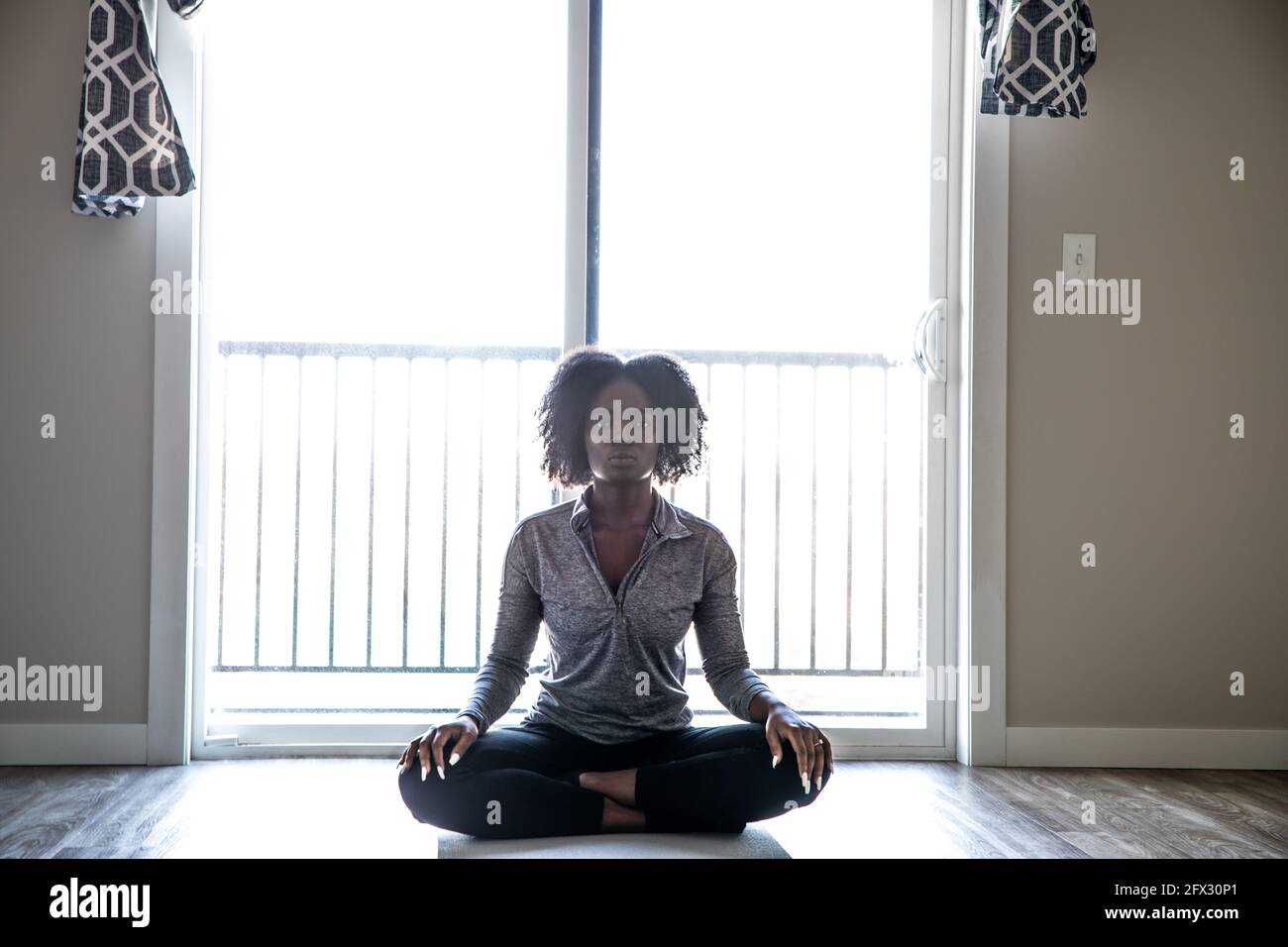 Schöne junge schwarze Frau, die in Yoga-Position sitzt und isoliert auf weißem Hintergrund meditiert. Stockfoto