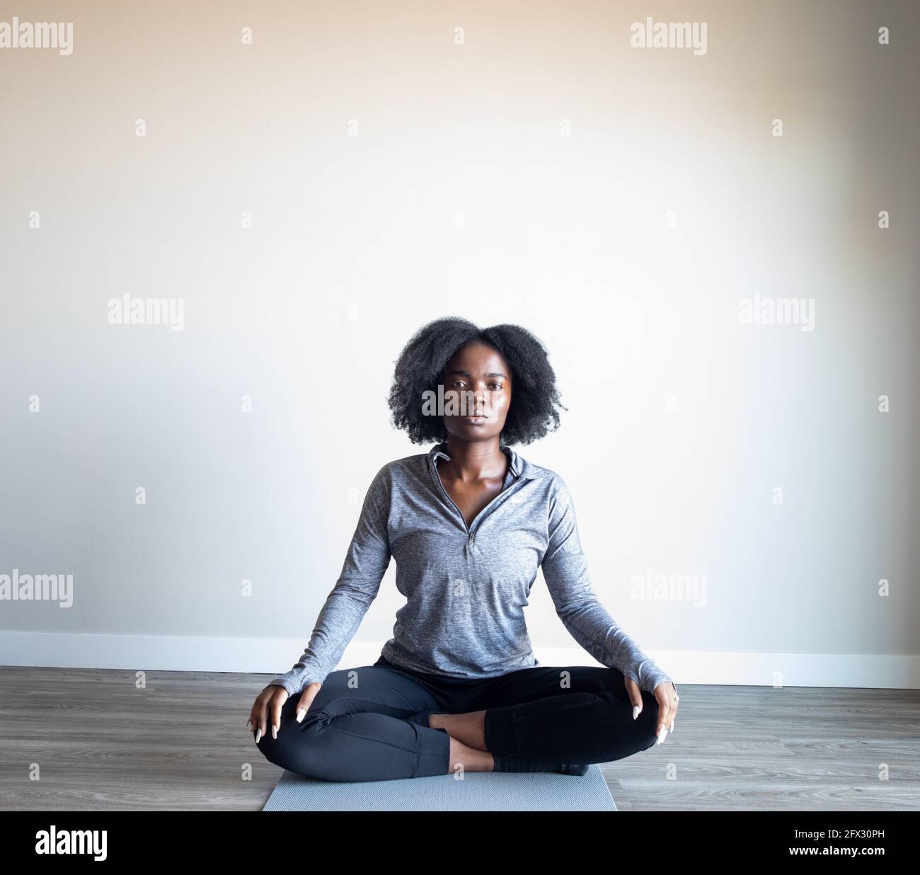 Porträt einer attraktiven, friedlichen jungen dunkelhäutigen Frau in Sportbekleidung, die in Innenräumen meditiert, eine Person, Gesundheit, aktiver Lebensstil, afroamerikaner, Stockfoto