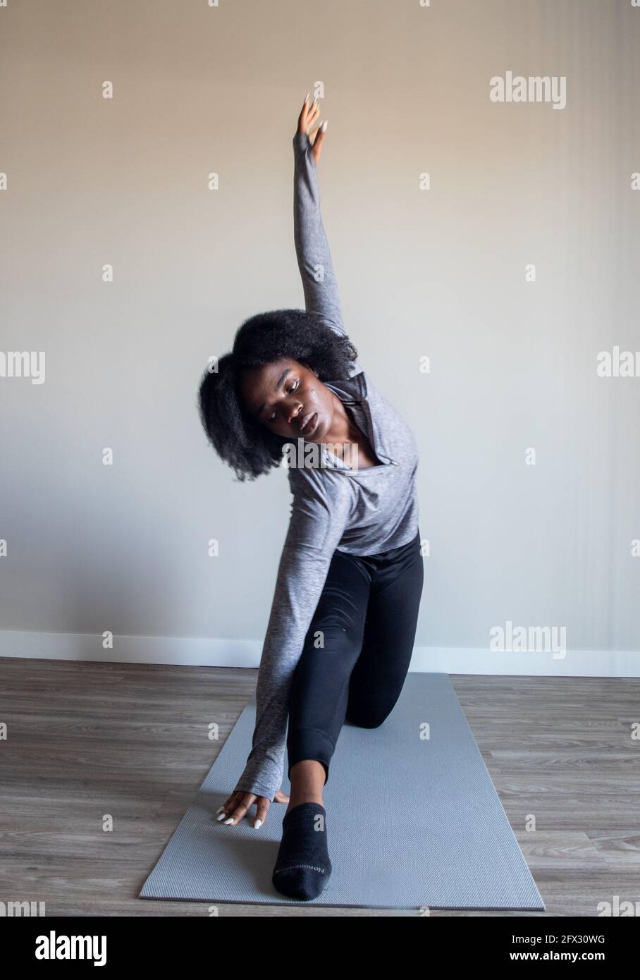 Frau praktiziert Yoga Asana im Heimstudio. Fitness Yoga, Entspannung, schwarze Frau, afroamerikanisch, natürliche Haare, Eine Person, Nahaufnahme, Stockfoto