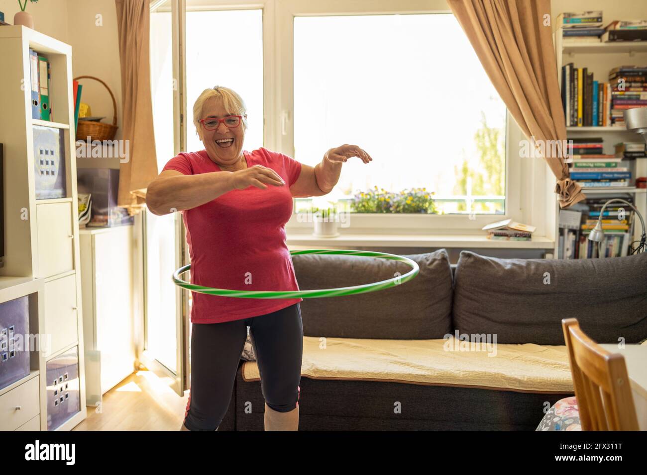 Ältere Frau Hula Hooping zu Hause Stockfoto
