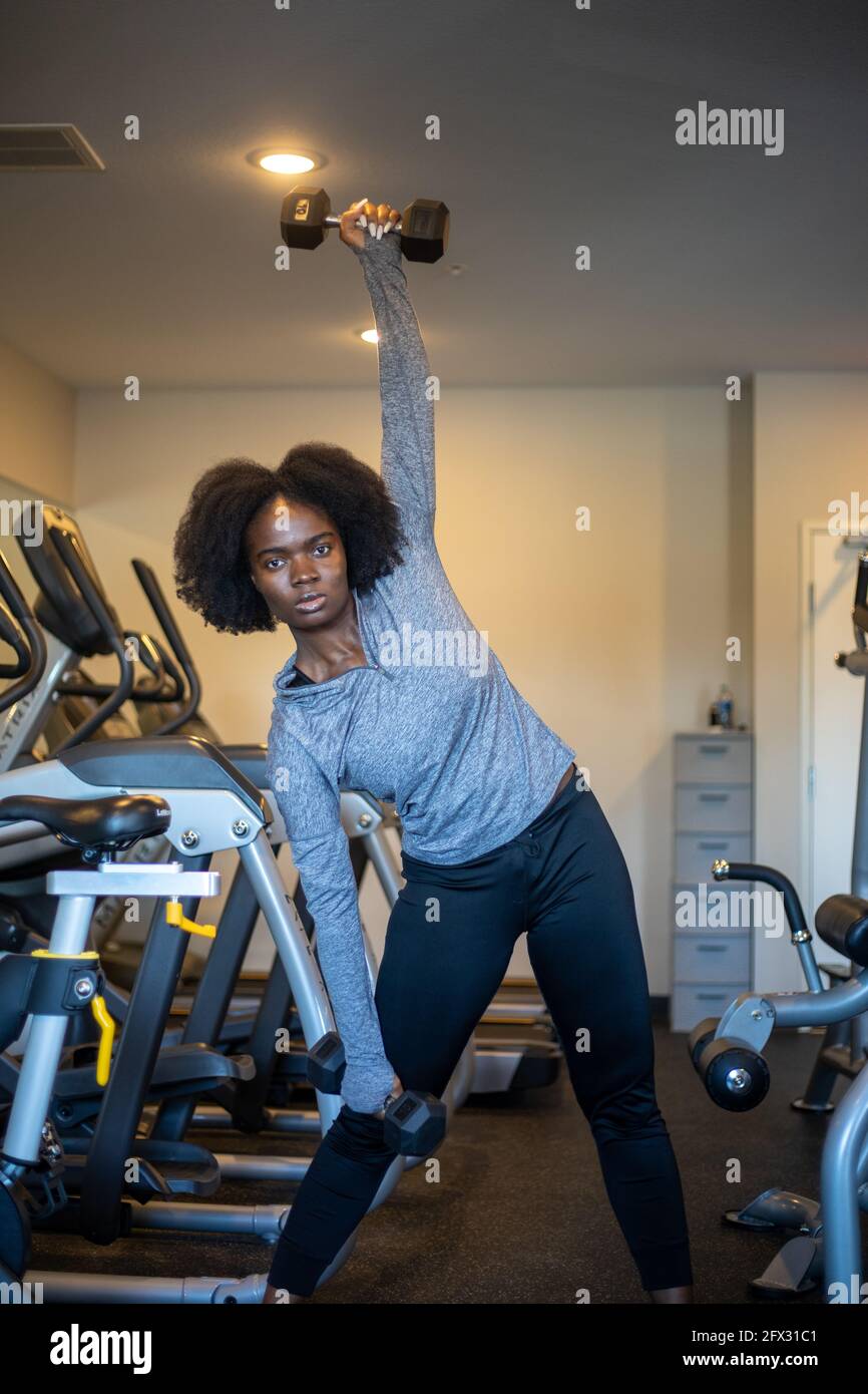 Grimmige Frau beim Training mit Hanteln im Fitnessstudio zu Hause. Nahaufnahme, eine Person, Fitnessmodell, afroamerikanisch, afrikanisches Modell, Sportswear, Natural Hair Mode Stockfoto