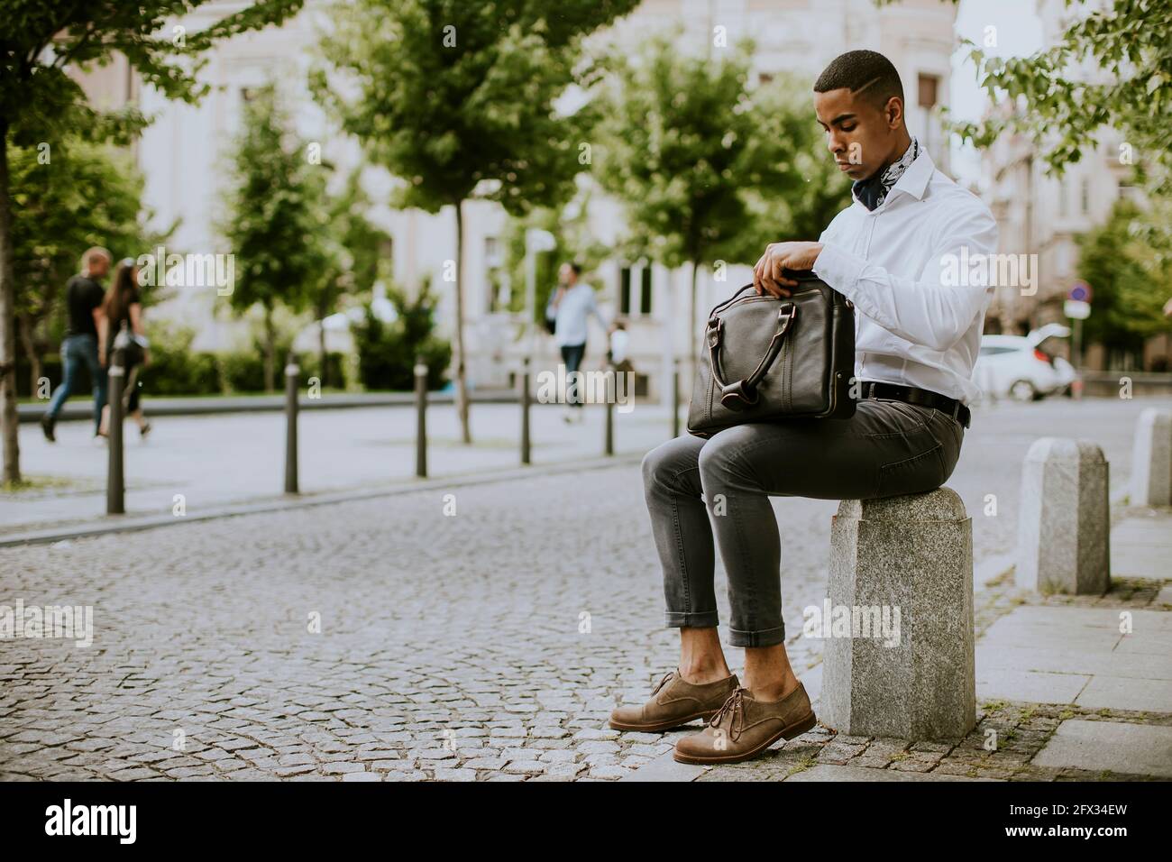 Hübscher junger afroamerikanischer Geschäftsmann, der ein Mobiltelefon benutzt Warten auf ein Taxi Warten auf ein Taxi auf einer Straße Stockfoto
