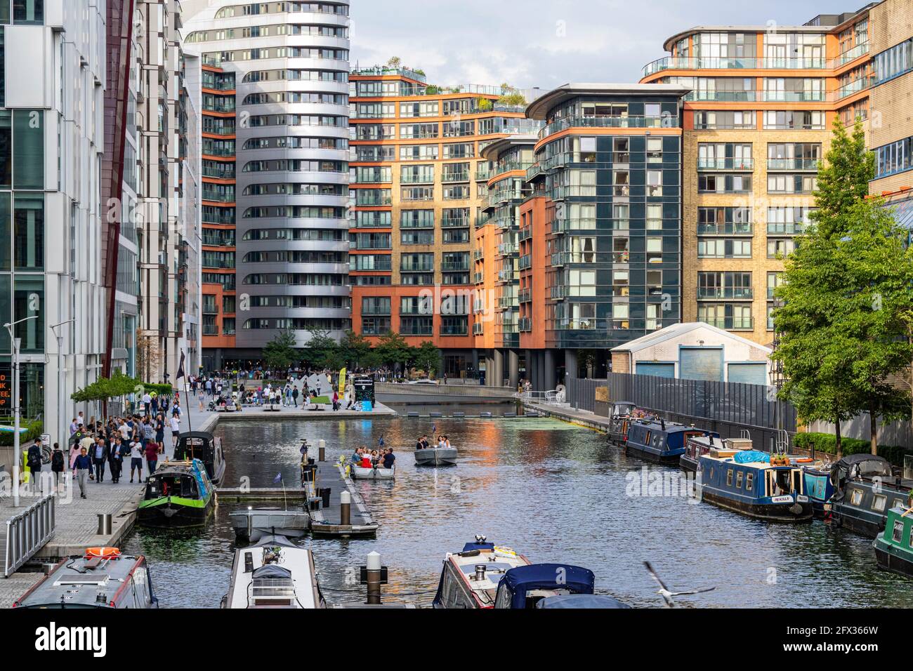 Farbenfroher Blick auf das Paddington Basin mit festgetäuten Bargen Happy People und modernen Gebäuden. Stockfoto