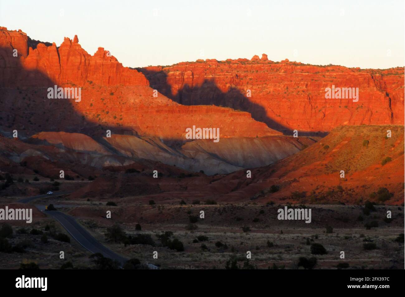 Das Licht am späten Nachmittag auf den Bergen des Waterpocket Fold, das sie in einer rötlich-goldenen Farbe färbt, wie vom Highway 24 in Utah USA aus gesehen Stockfoto