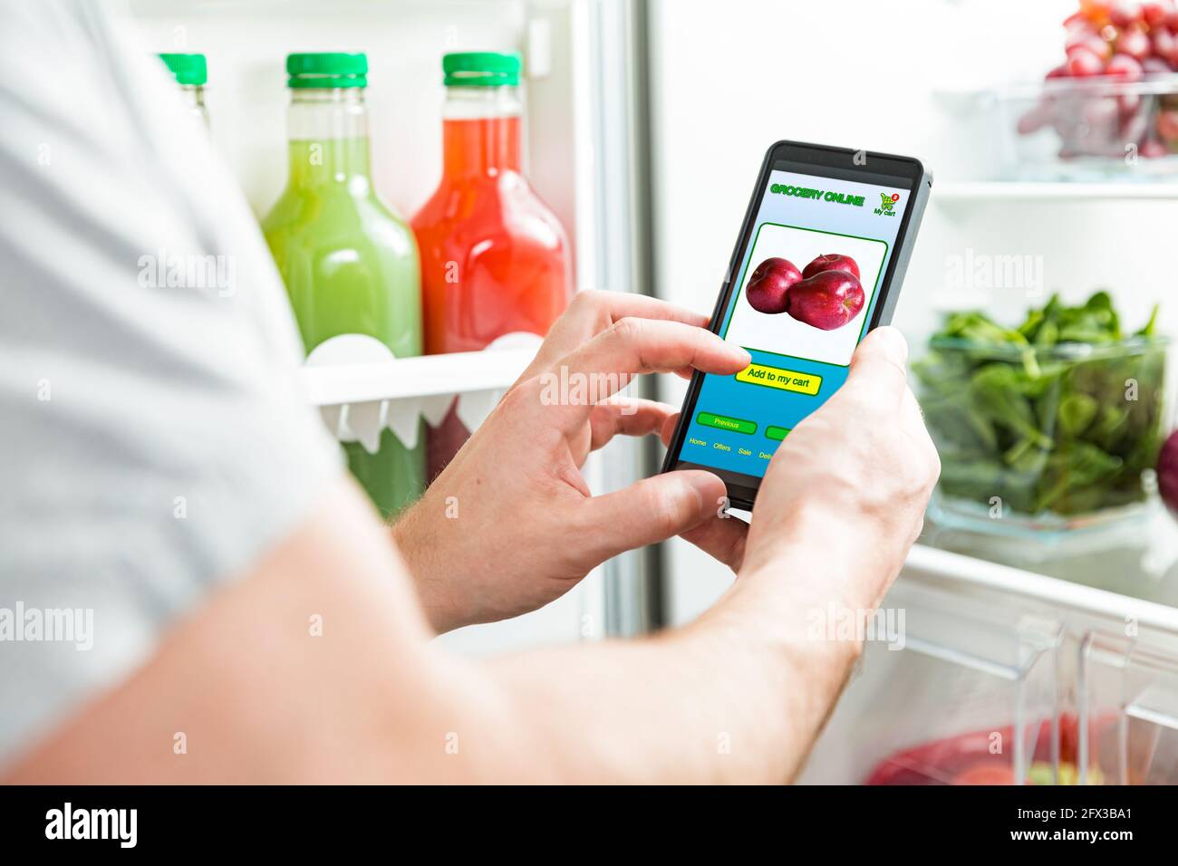 Mann mit Smartphone, Lebensmittel kaufen. Nahaufnahme mit Telefon. Lebensmitteleinkäufe online. Mobile App des Online-Lebensmittelgeschäft. Frisches Gemüse im Kühlschrank Stockfoto