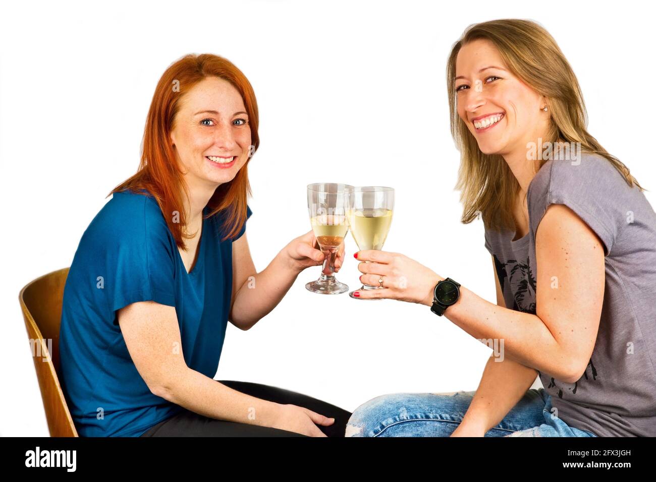 Zwei junge attraktive lachende Frau, die mit Weingläsern klirren (Cheers!). Isoliert auf weißem Hintergrund. Stockfoto