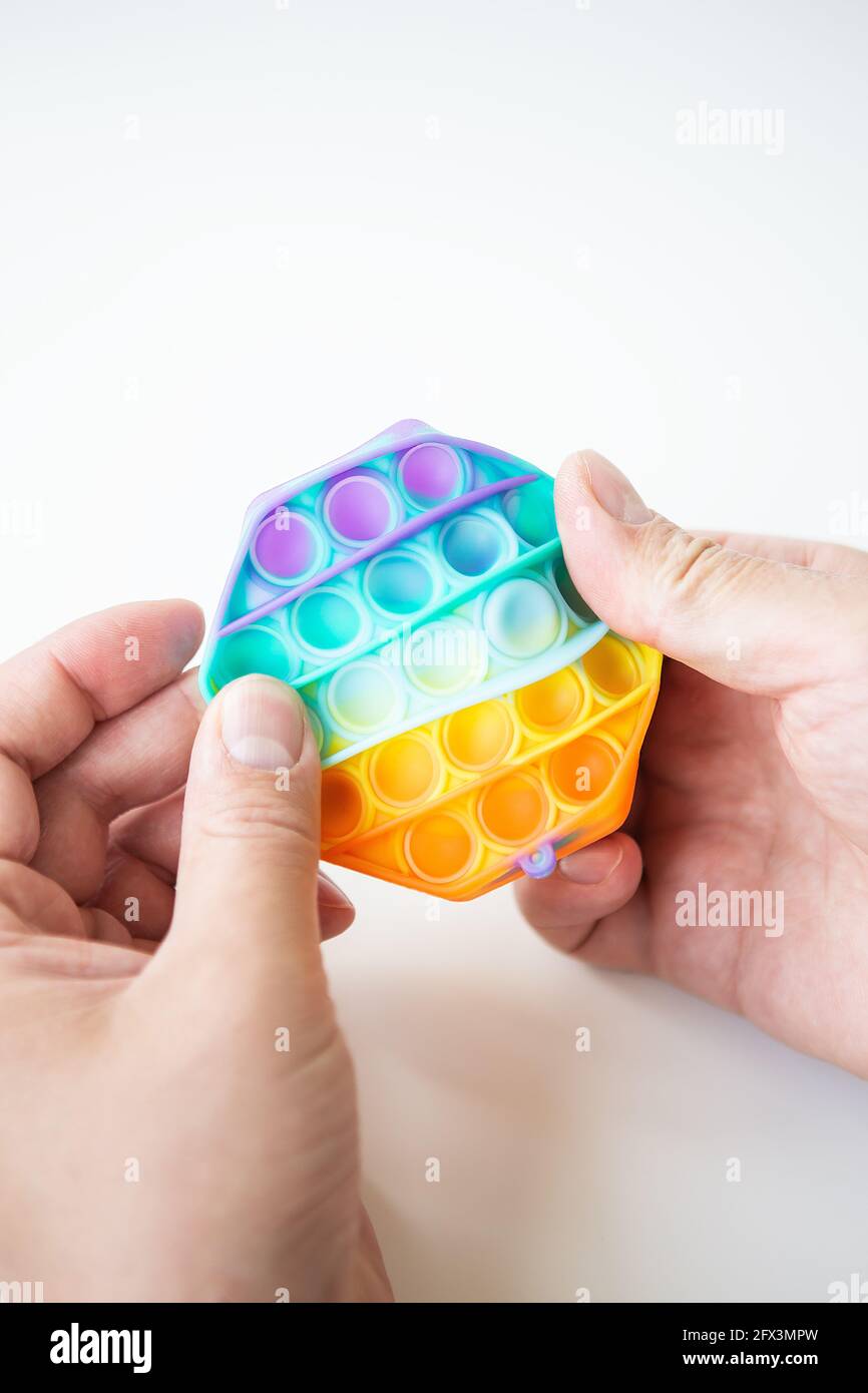 Das modischste Sinnesspielzeug. Neue beliebte bunte Anti-Stress-Spielzeug  Pop es in Form eines Sechsecks in der Hand. Fidget Spielzeug Rainbow Pop  Stockfotografie - Alamy