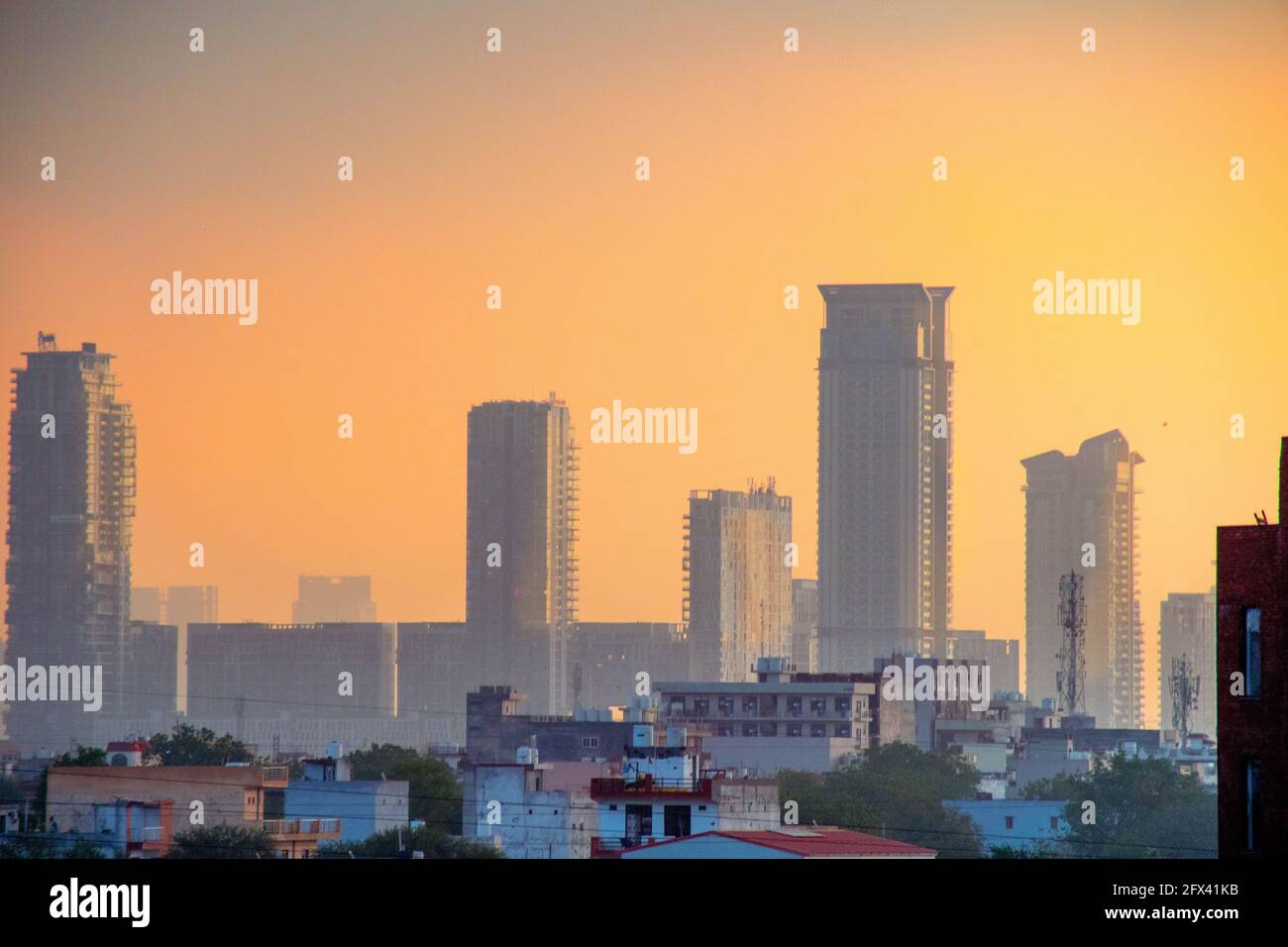Dämmerung von Wolkenkratzern Häuser geschossen teilweise im Nebel versteckt mit dem warmen Orange der Dämmerung zeigt den Beginn eines neuen Tages in gurgaon, delhi, indien Stockfoto