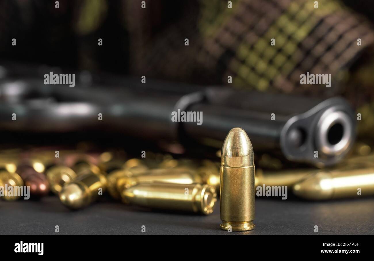 Einzelne gelbe Messing Kugel Detail, schwarze Metallpistole im Hintergrund Stockfoto