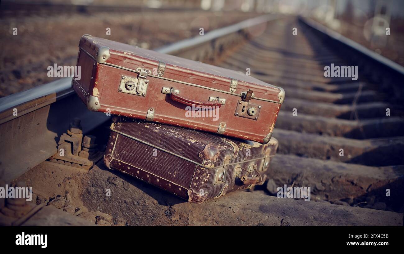 Das Bild von zwei alten Vintage-Koffern, die auf Eisenbahnschienen geworfen wurden. Stockfoto