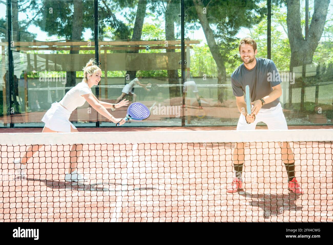 Gemischtes Paar spielt auf einem Padel-Platz im Freien in einem Sonniger Sommertag Stockfoto