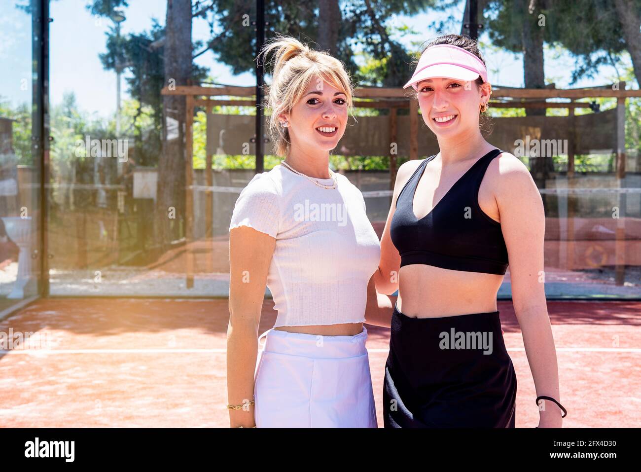 Zwei lächelnde und siegreiche Mädchen posieren für ein Foto auf Ein Tennisplatz Stockfoto