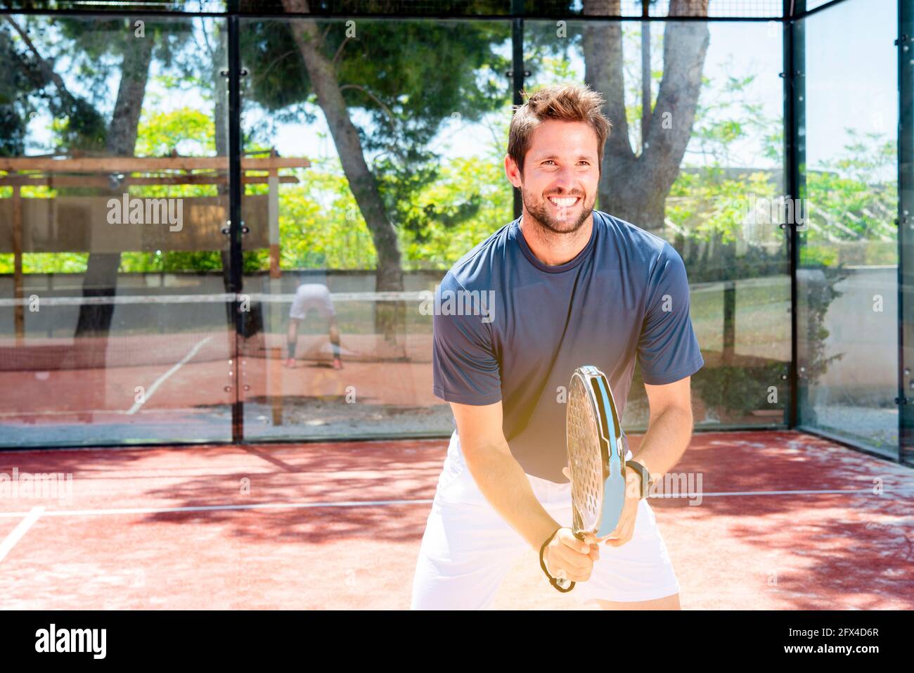 Junger Mann spielt Padel Tennis im Freien Sommer Sportplatz bekommen Passform Stockfoto