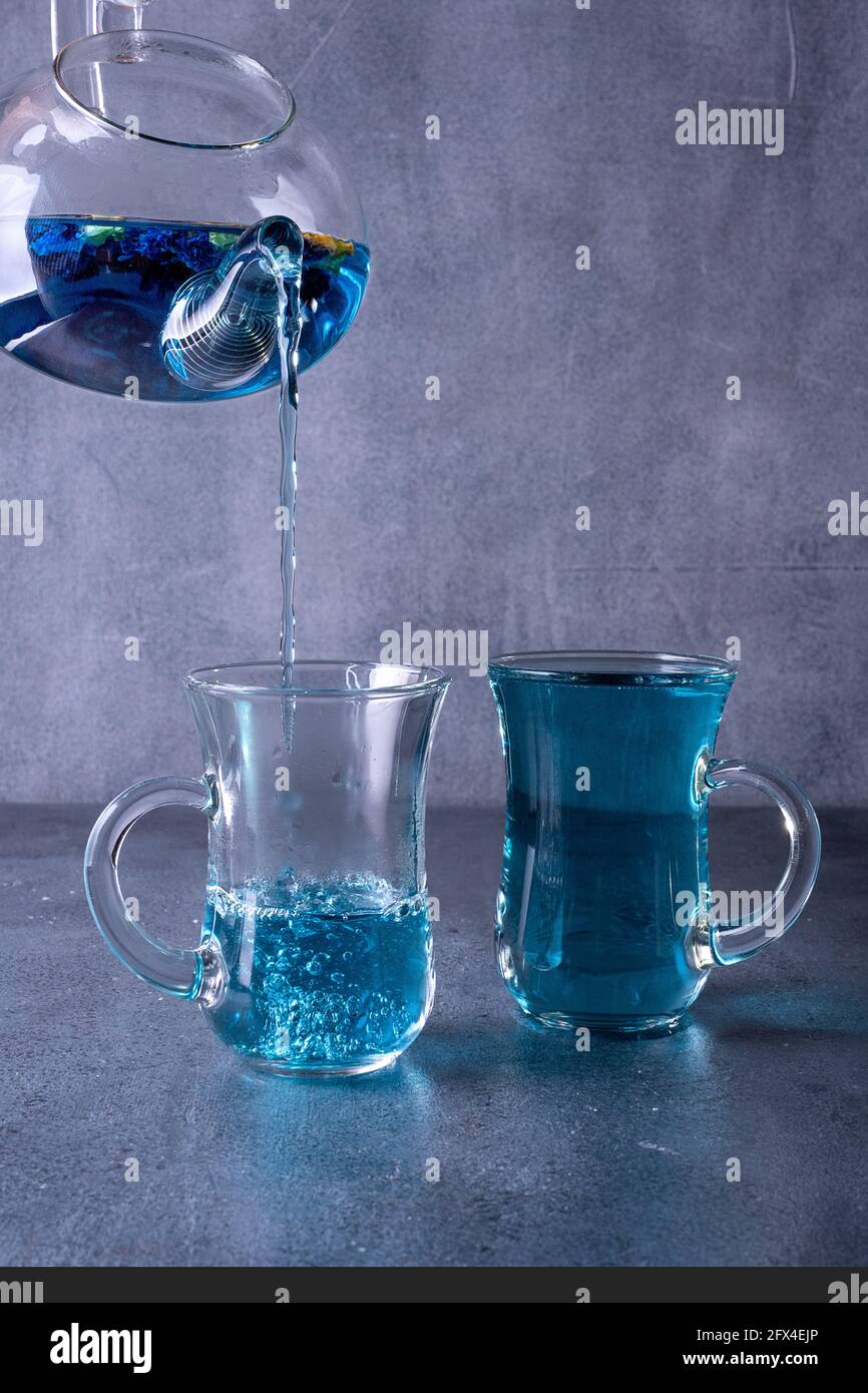 Teekannen blau Thai Gießen Tee in eine Tasse auf grau Hintergrund Stockfoto