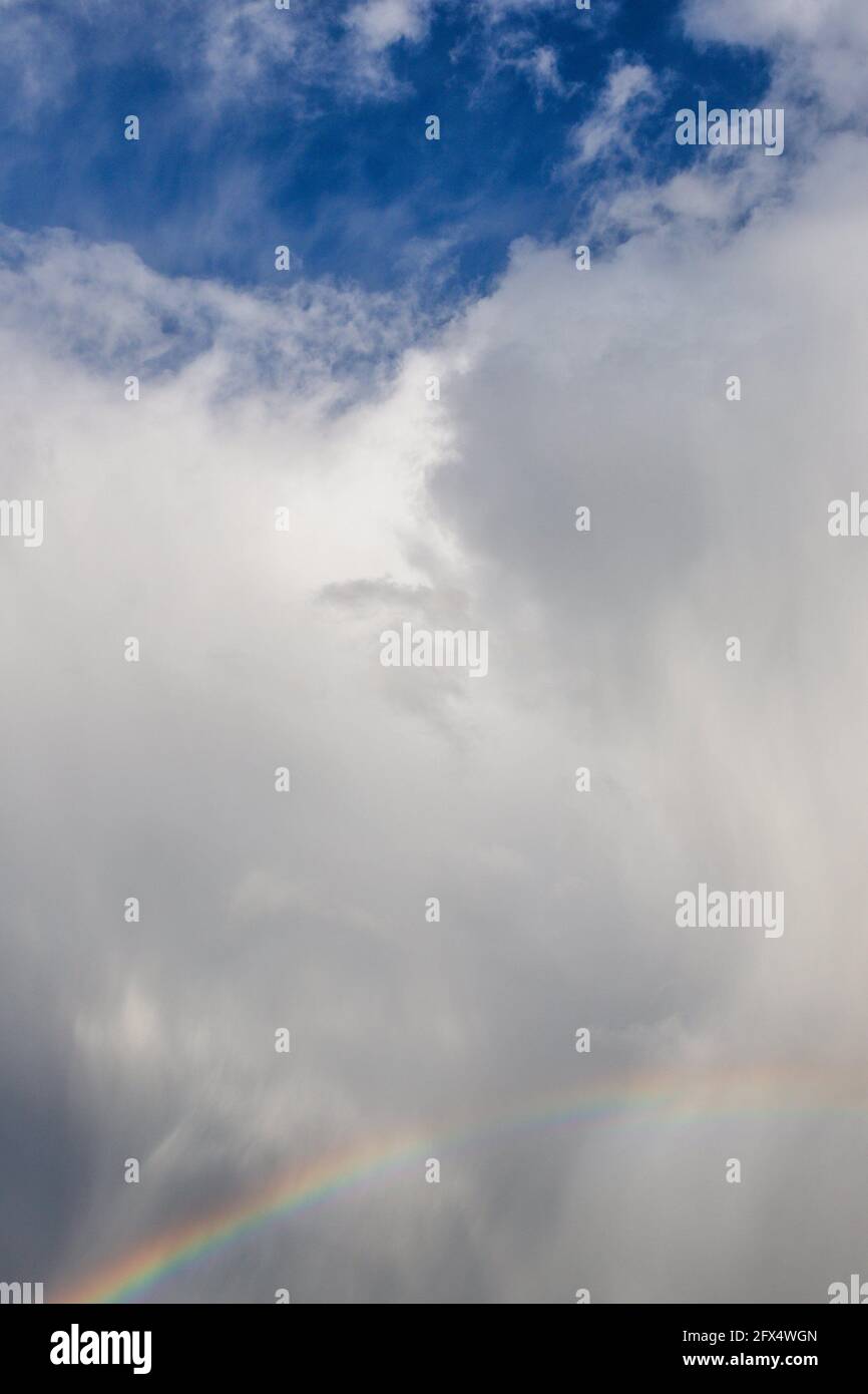 Regenbogen und regnerisch grau weiß blauer Himmel mit flauschigen Wolken Stockfoto