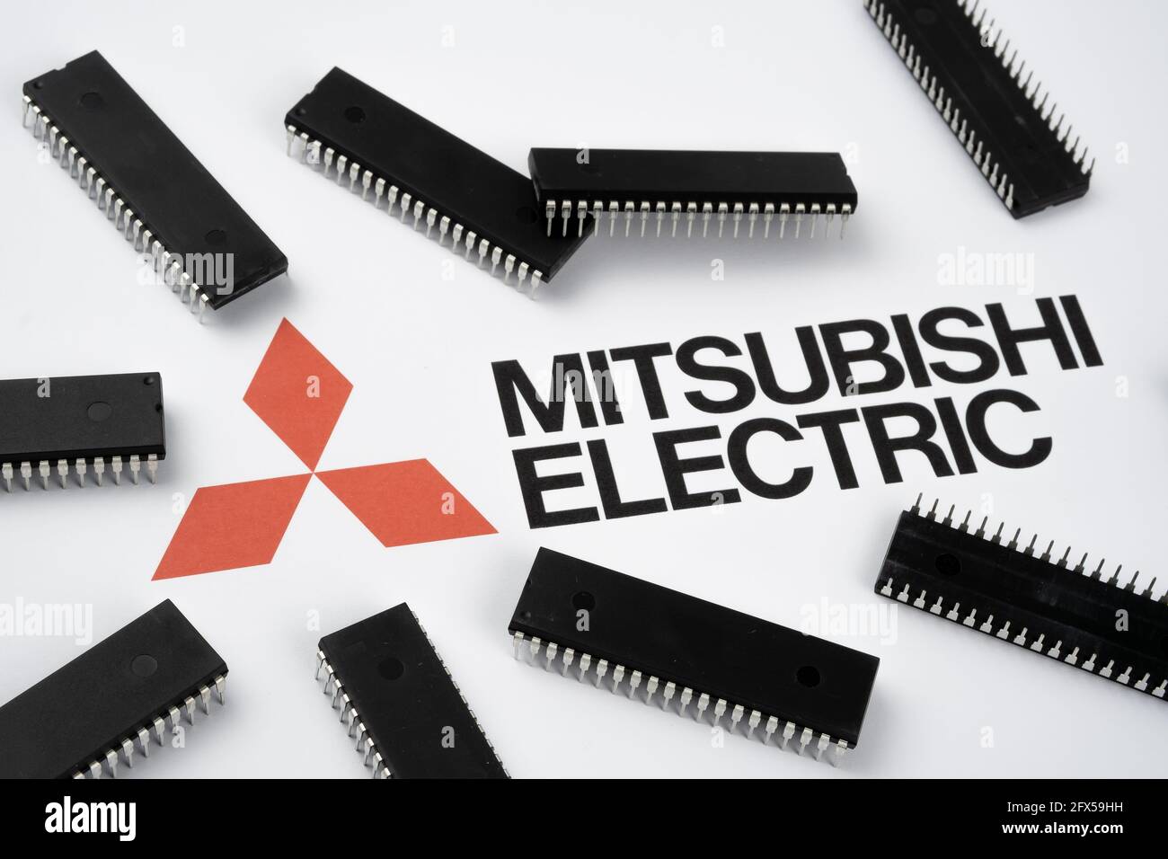 Mitsubishi Electric Firmenlogo auf dem Papierdokument und große Mikrochips, die um das Dokument herum platziert wurden. Illustration für den Hersteller von elektronischen Chips. Selektiv f Stockfoto