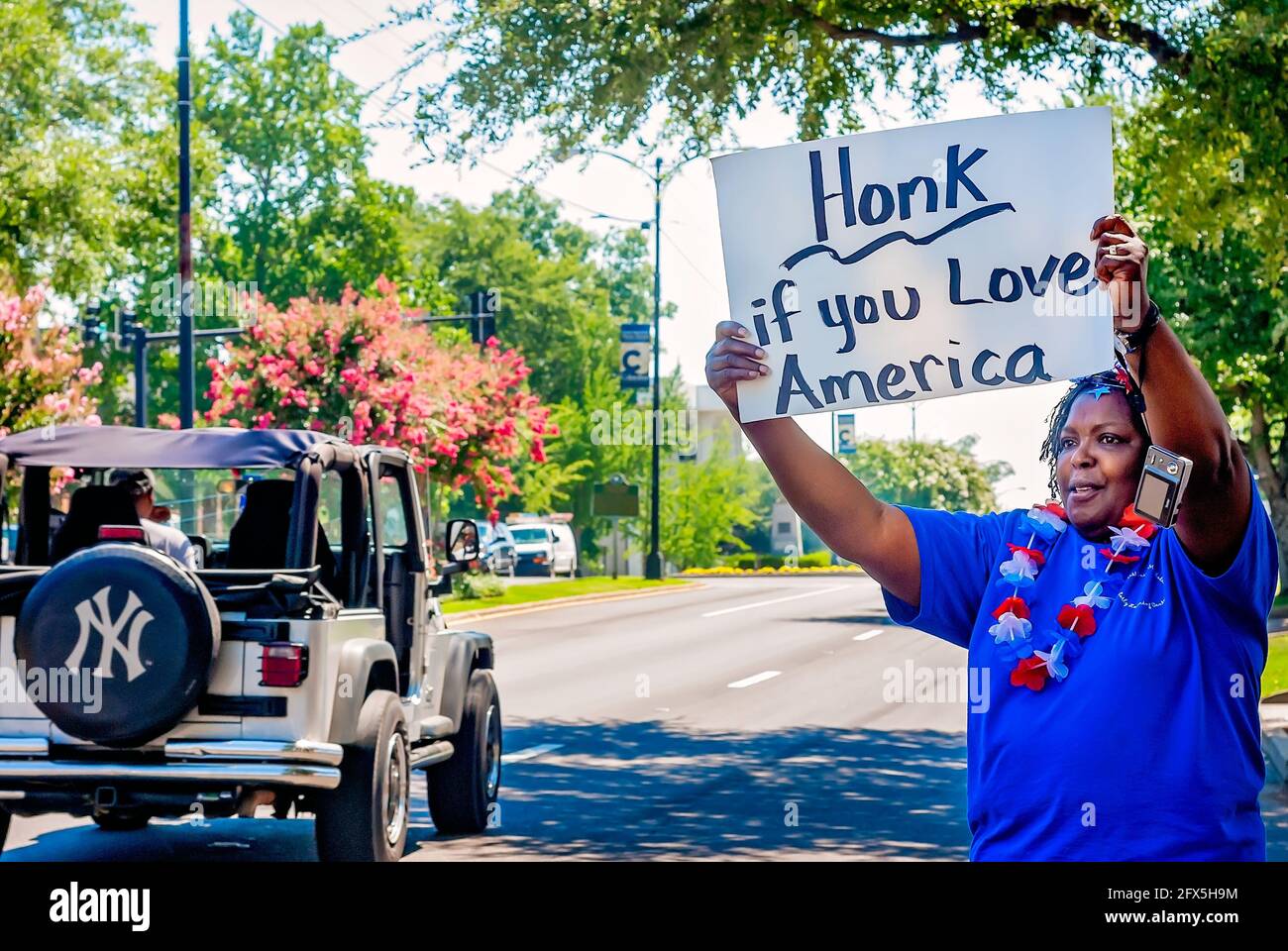 Am 30. Juni 2011 in Columbus, Mississippi, hält eine afroamerikanische Frau ein Schild, das Autofahrer dazu auffordert, ihre Autohupe zu hupen, wenn sie Amerika lieben. Stockfoto