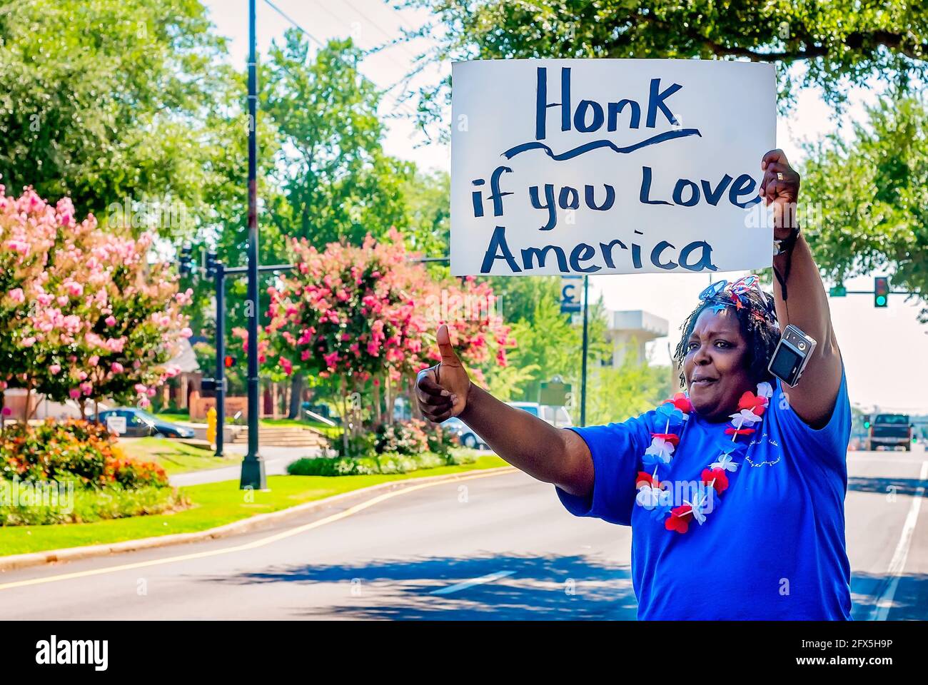 Am 30. Juni 2011 in Columbus, Mississippi, hält eine afroamerikanische Frau ein Schild, das Autofahrer dazu auffordert, ihre Autohupe zu hupen, wenn sie Amerika lieben. Stockfoto